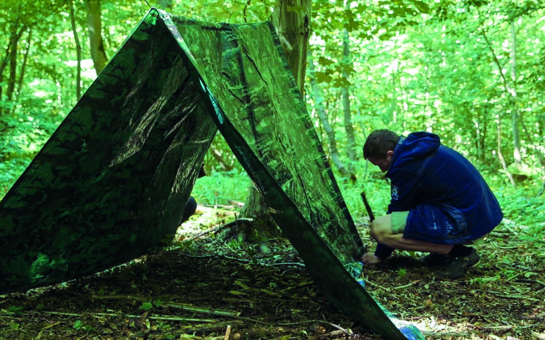 Ein Teilnehmer des Survival-Camps in der Wildnis Deutschlands baut sein Zelt auf