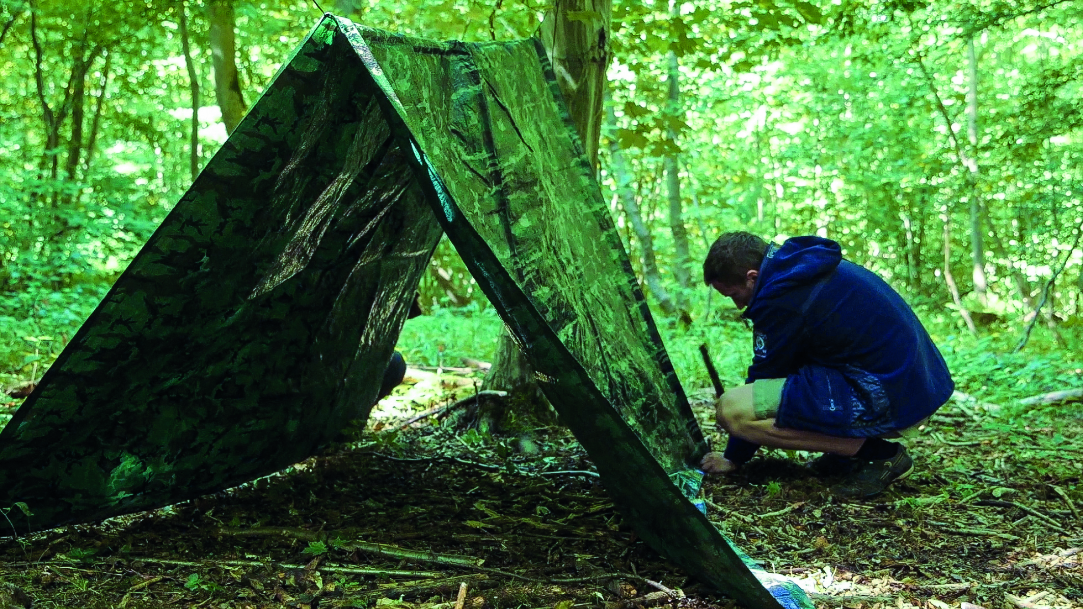 Ein Teilnehmer des Survival-Camps in der Wildnis Deutschlands baut sein Zelt auf