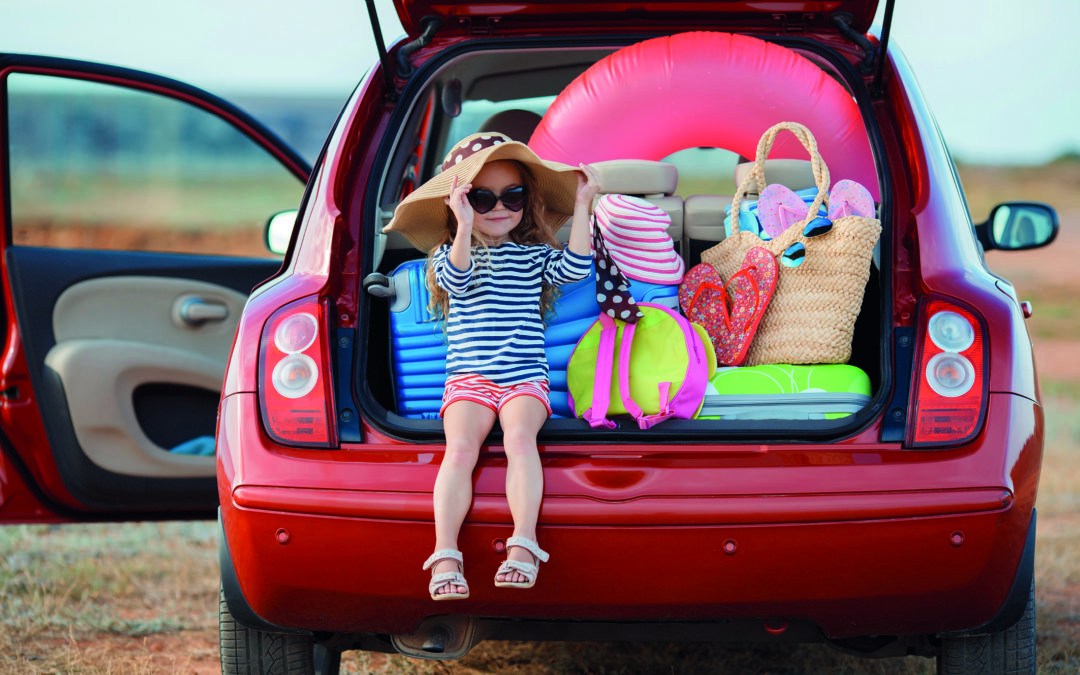 Ein Kind sitzt im geöffneten Kofferraum.