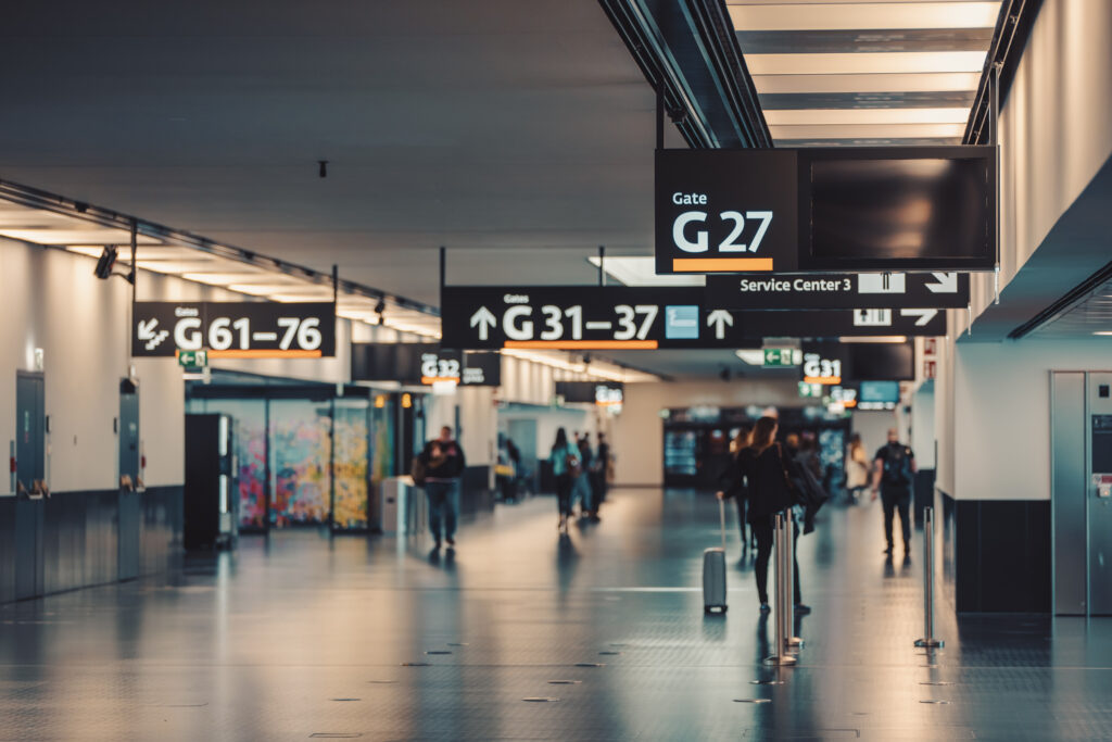 Checkliste Urlaub: Leerer Gang eines Flughafens mit den Gate Überschriften.