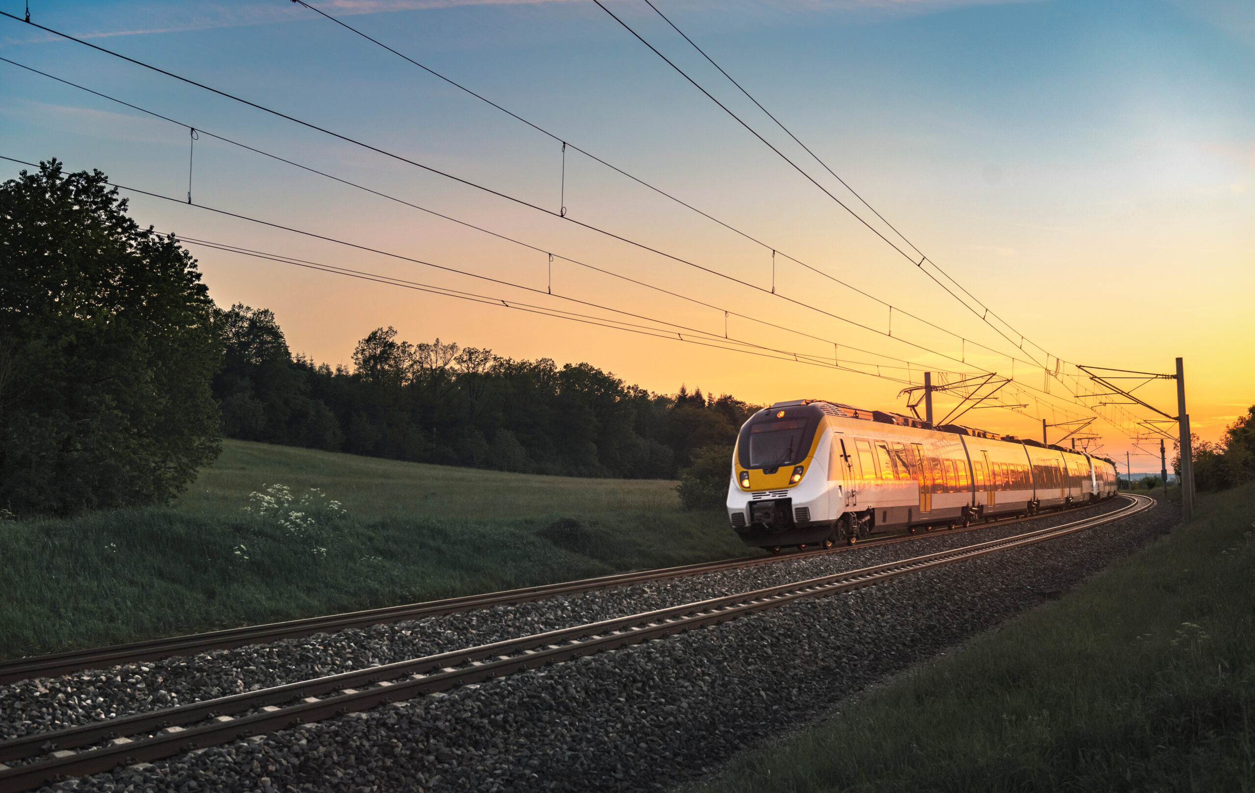 Zug auf Gleisen fährt im Sonnenuntergang.